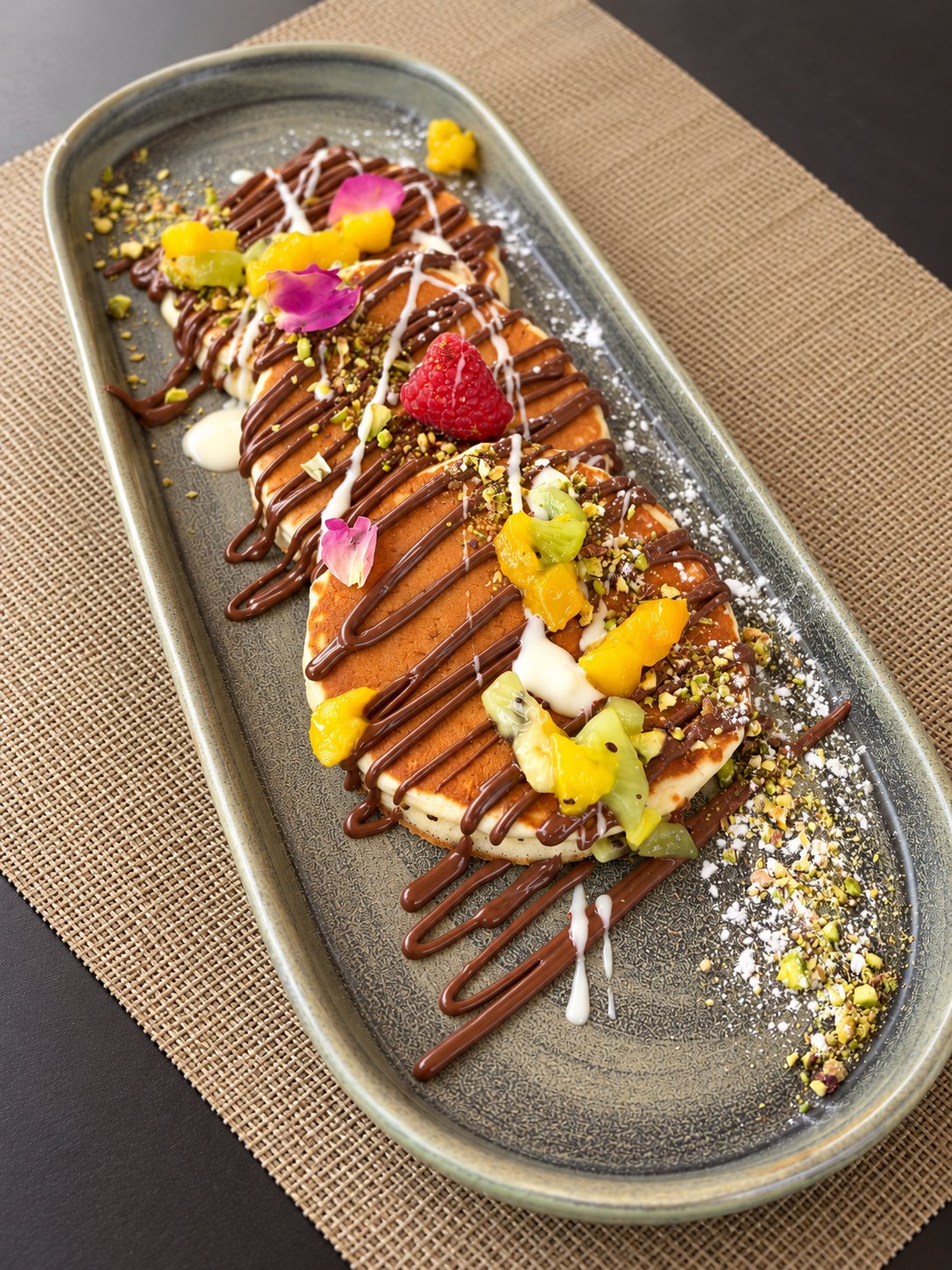 Douceur au chocolat et aux fruits, décorée de fleurs, sur un plat long